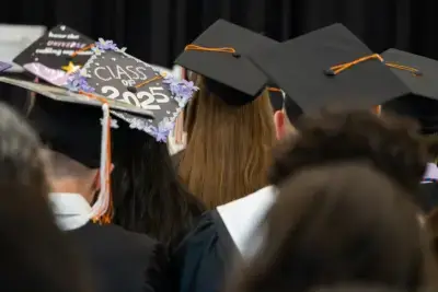 Graduates wearing caps and gowns are seen from behind