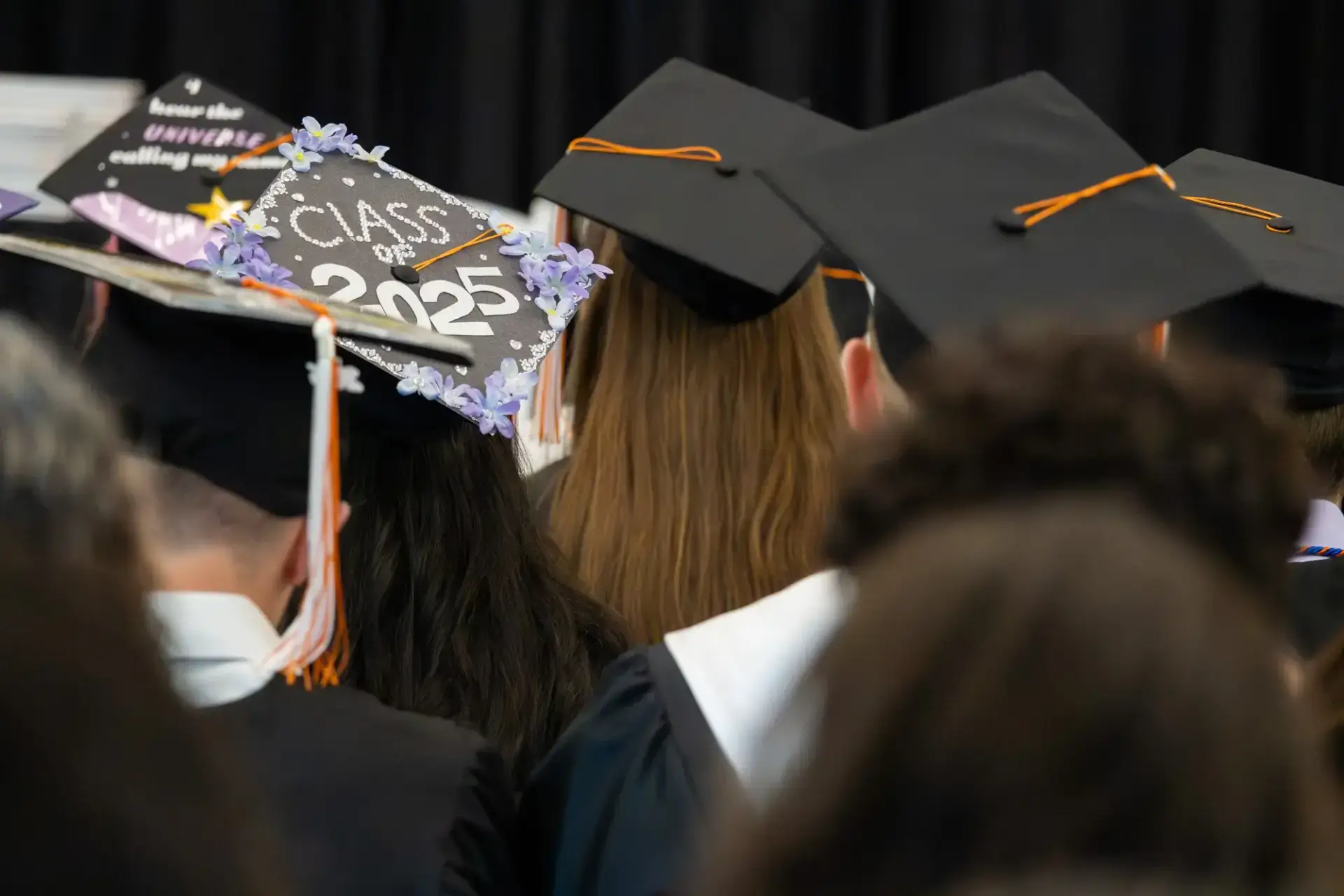 Graduates wearing caps and gowns are seen from behind