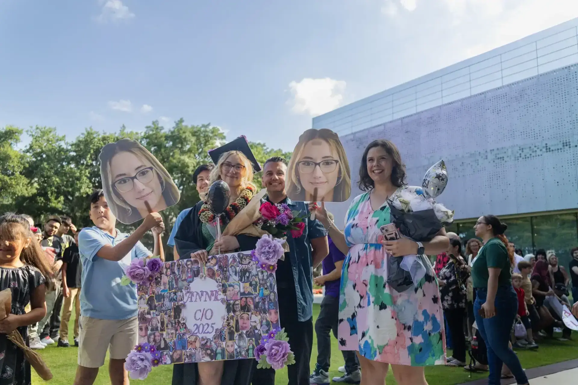 A joyful outdoor graduation scene with a graduate in a cap and gown holding flowers